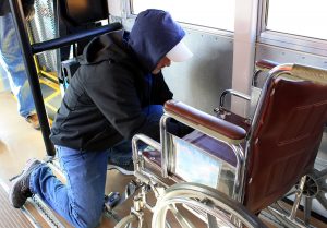 A school bus driver secures a wheelchair on the bus.