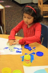 A preschooler plays with play dough during class