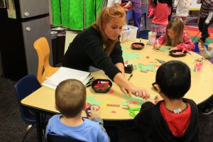 Photo of a Johnston preschool classroom with a teacher helping students.